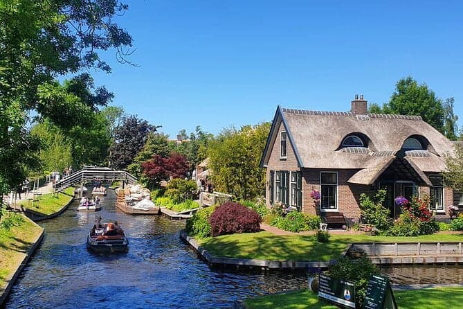 Een fluisterboot in de gracht van Giethoorn, langs een rietgedekte woning